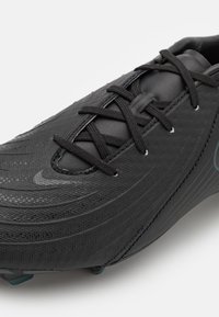 Crampon de football noir avec un dessus texturé, doté de lacets, d'une forme épurée et de lignes distinctes ; comprend un logo discret et des crampons moulés.
