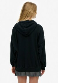 Sort hætte sweatshirt med en blød tekstur, oversized pasform og ribbet kant. Har en kængurulomme og subtile syninger.