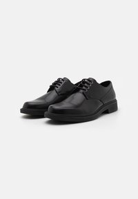 Scarpe da uomo in pelle nera con finitura lucida, punta tonda e sistema di allacciatura a 5 fori. Suola piatta in gomma; dettagli di cucitura minimi.