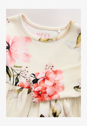 Jasnokremowa sukienka wykonana z prążkowanej tkaniny, z kwiatowymi wzorami w kolorach różowym i zielonym oraz falbaniastym mankietem. Metka marki widoczna wewnątrz przy dekolcie.