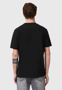 T-shirt nera a maniche corte realizzata in morbido cotone, con un classico colletto a girocollo e una vestibilità rilassata, cuciture visibili e senza grafica.