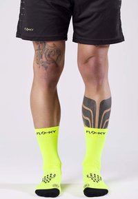 Calzini sportivi giallo neon con texture a coste e scritte nere. Presentano un motivo a pois sulle suole per una migliore aderenza e trazione.