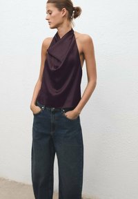 Dark purple halter top with draped fabric, paired with high-waisted dark blue wide-leg jeans, featuring front pockets and a relaxed fit.