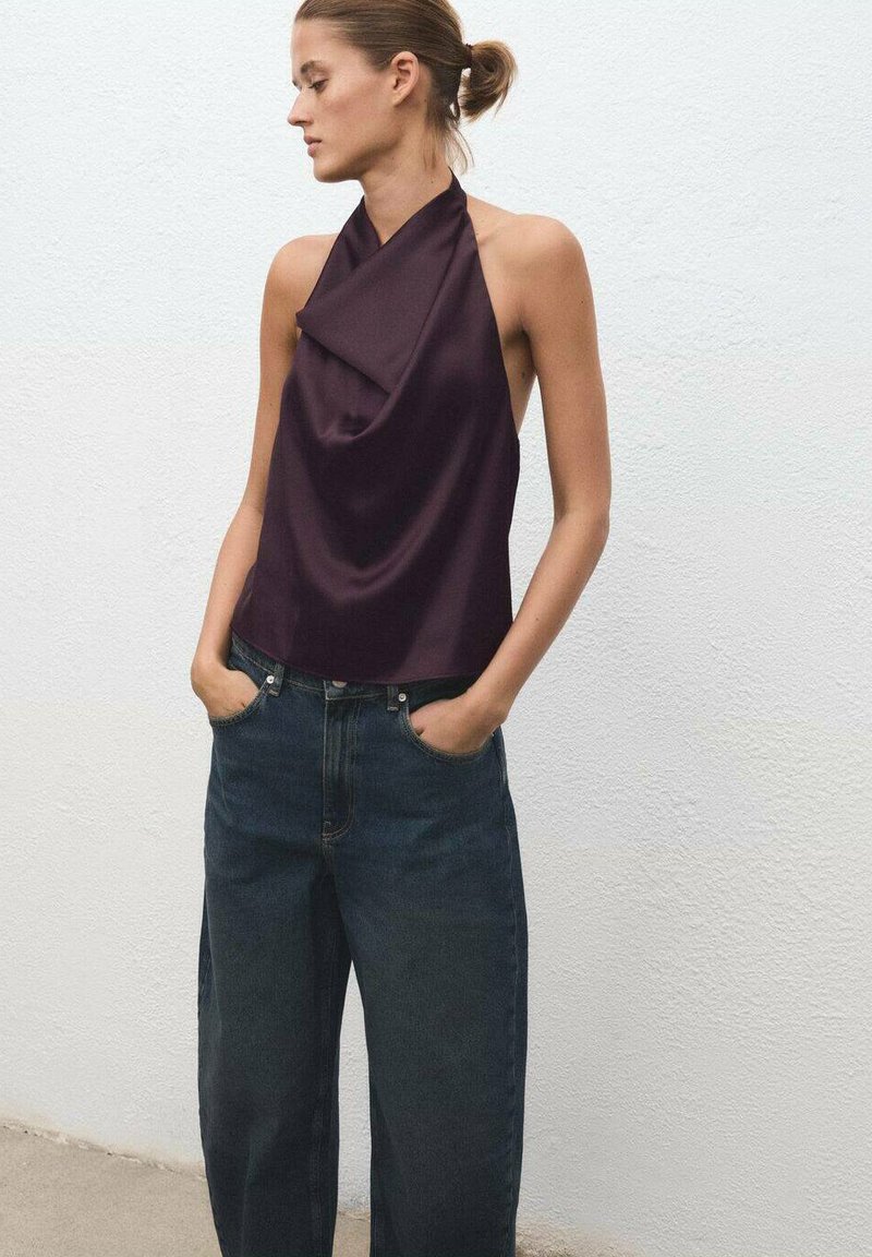 Dark purple halter top with draped fabric, paired with high-waisted dark blue wide-leg jeans, featuring front pockets and a relaxed fit.