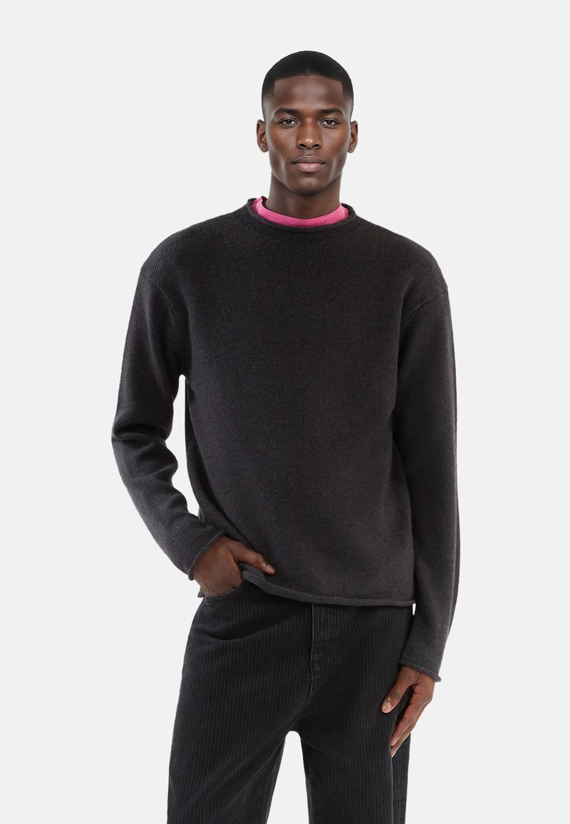 Dark gray knitted sweater with a round neckline, long sleeves, and a relaxed fit, paired with matching dark corduroy pants.