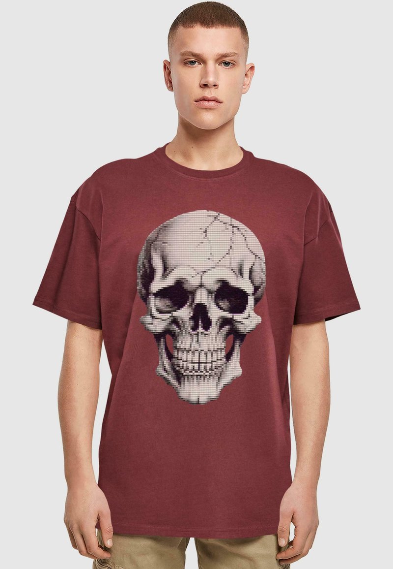 Mørkerød oversized t-shirt lavet af bomuld, med et detaljeret grafisk motiv af et kranium i kontrastfarver på forsiden. Korte ærmer.