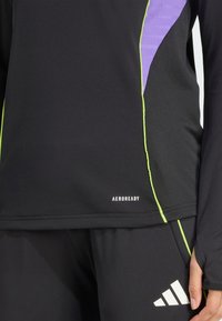Crni dugosleeve atletski top s ljubičastim i zelenim detaljima, logom "AEROREADY", gladak teksturiran i prilagođen kroj.