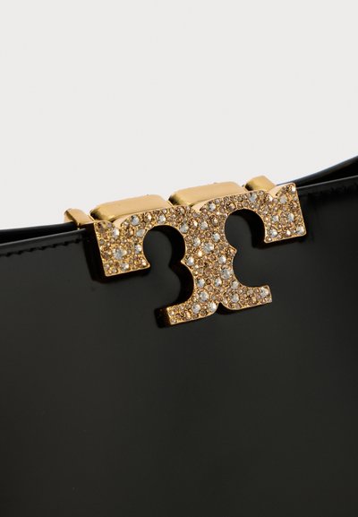 Melnas laku ādas somiņas ar zelta sprādzi, kas ir izrotāta ar maziem caurspīdīgiem kristāliem simetriskā dizainā.