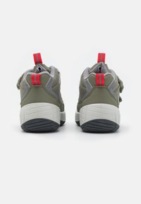 Zielone sportowe buty z szarymi akcentami, teksturowany materiał, białe środkowe części oraz czerwone pętle na pięcie. Odpowiednie do noszenia na co dzień.