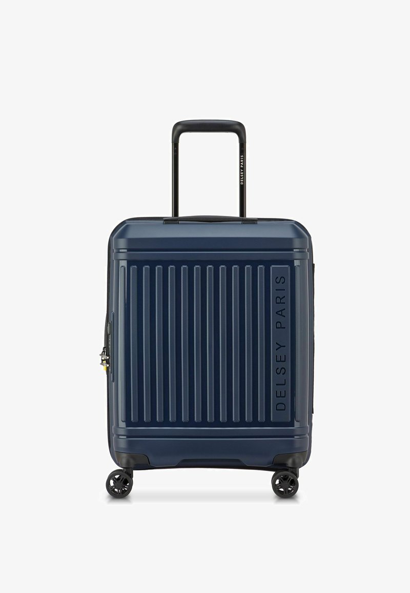 Maleta dura navy con surcos verticales, asa retractable negra, cuatro ruedas y el logo de Delsey Paris grabado en el lateral.