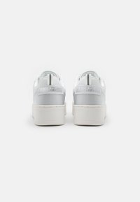 Sneaker bianche con una tomaia sintetica liscia, suola a piattaforma rialzata e sottili dettagli con logo sul tallone. Punta arrotondata e colletto imbottito.