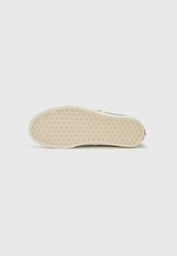 Sole of a sneaker with a rubber, textured surface in off-white color, featuring a diamond pattern for traction and grip.