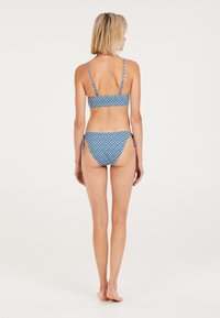 Modrý bikiny set s geometrickými vzormi, tenkými nastaviteľnými popruhmi a jednoduchým dizajnom. Tkanina je jemná s ľahkou textúrou.