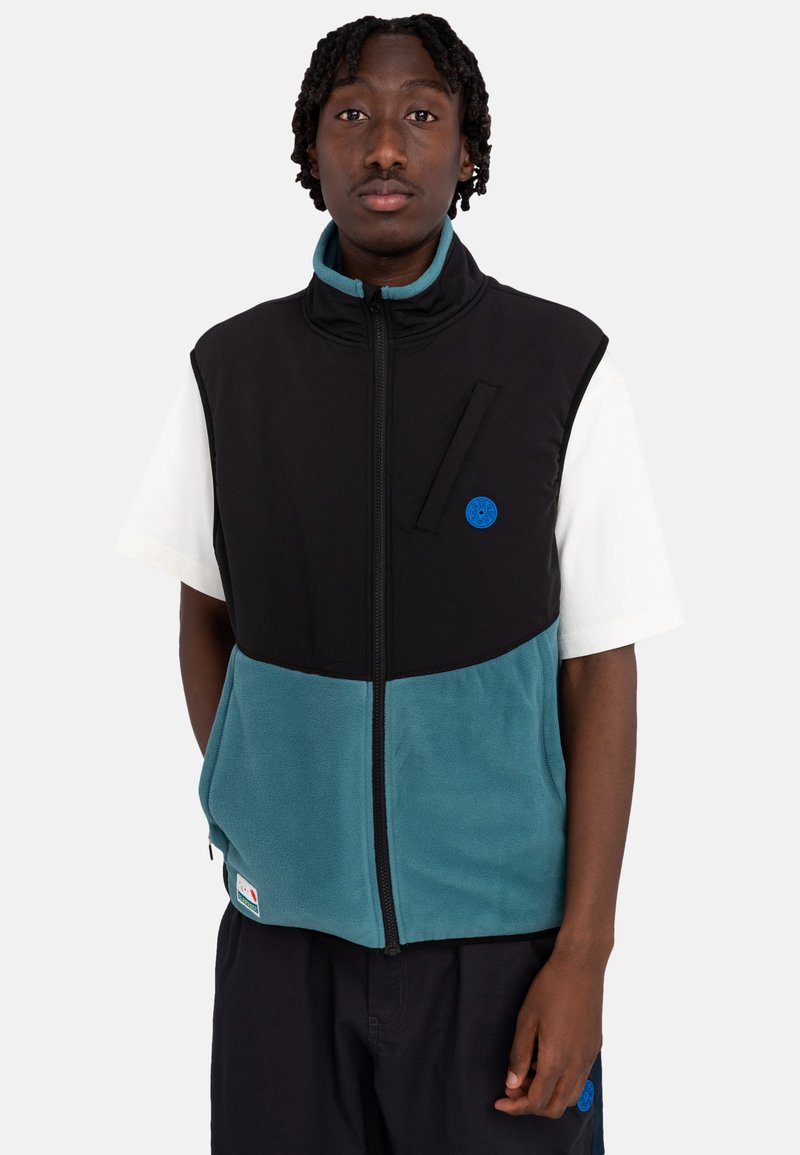 Black and teal fleece vest with full zip, stand collar, and front pocket detail. Features a blue circular logo and contrasting panel design.