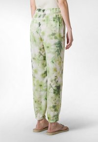 Leichte, elastische Bundhose im grün-weißen Aquarell-Blumenmuster mit schmal zulaufenden Abschlüssen. Hergestellt aus weichem, fließendem Material.