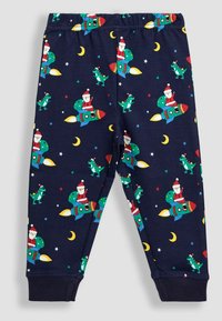 Pantalones de pijama de algodón azul marino con patrones de cohetes, dinosaurios y Papá Noel, que presentan lunas y estrellas amarillas; cintura elástica y puños elásticos.
