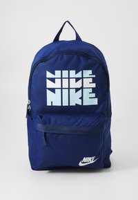 Tamno plavi ruksak od teksturirane tkanine, s velikim bijelim i svijetloplavim Nike logotipom sprijeda i džepom sa zatvaračem.