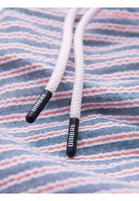 Cordons blancs avec embouts noirs portant la mention "DIMBRE" sur un fond en tissu rayé bleu, blanc et rouge.