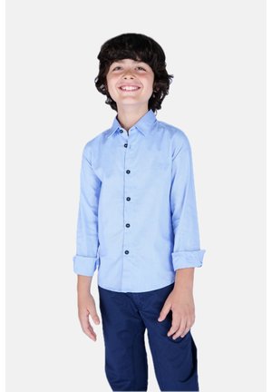 Camicia azzurra chiara a maniche lunghe con chiusura a bottoni, polsini ripiegati e bottoni scuri. Indossata con pantaloni blu navy. Design semplice, senza motivi.