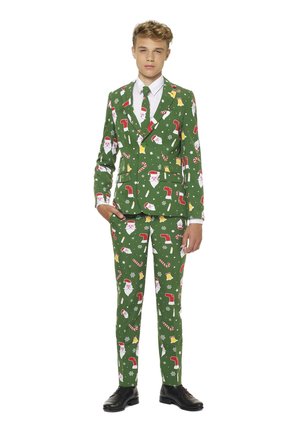 Groen pak bedekt met feestelijke patronen, waaronder een kerstman, kerstkousen, zuurstokken en bellen, met bijpassende stropdas en glanzende zwarte schoenen.