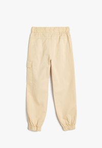 Beige cargo bukser med elastisk talje og manchetter, med sidelommer og et blødt, struktureret bomuldsstof.