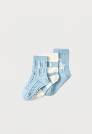 Tre calzini per neonati in azzurro chiaro e bianco: uno a trecce, uno a righe e uno con il disegno di un giocatore di polo.