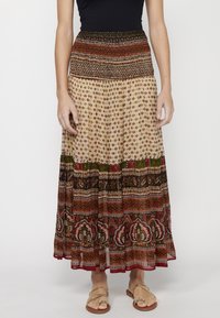 Maxi skirt with a smocked waist in a cream base featuring multicolored floral and geometric patterns. Lightweight, flowing fabric with layered hem.