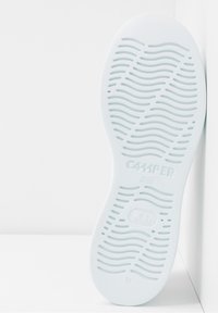 Suela de zapato de goma blanca con patrones ondulados texturizados, con la marca "CAMPER" y la talla "38". Acabado liso y forma curva.