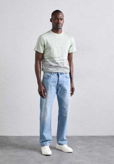 Light green t-shirt with a horizontal striped pattern in gray, paired with faded blue jeans and white sneakers. Simple, casual design.