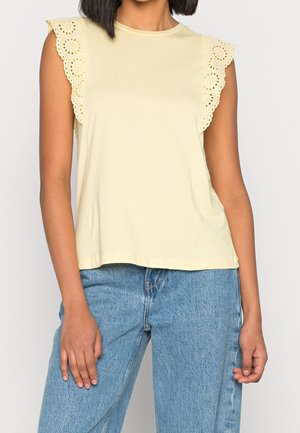 Helles gelbes ärmelloses Oberteil mit floralen Spitzenakzenten an den Schulternähten, mit rundem Halsausschnitt und einem lockeren Schnitt. Kombiniert mit Denim-Jeans.