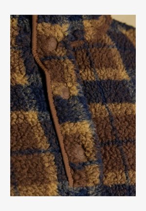 Brązowa, niebieska i żółta w kratkę tkanina polarowa o miękkiej teksturze; posiada plastikowe napy i kontrastujące brązowe wykończenie wzdłuż krawędzi.