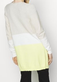 Strickpullover mit Rundhalsausschnitt, versehen mit einem Verlaufdesign in Beige, Weiß und leuchtendem Gelb. Weicher Stoff und lange Ärmel.