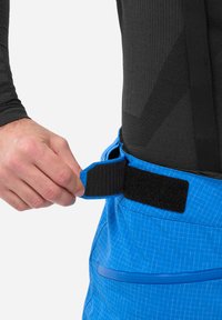 Blaue Cargo-Shorts mit einem Rautenmuster, ausgestattet mit einem Klettverschluss und einer glatten Textiloberfläche. Hand justiert den Taillenbund.