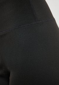 Zwarte athleisure leggings gemaakt van een gladde, rekbare stof met platte naden en een hoge tailleband voor comfort.