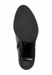 Chaussure en cuir noir avec une tige lisse, un bout rond et une semelle en caoutchouc texturée avec détail antidérapant et marquage de taille.