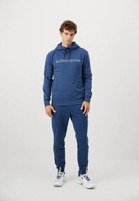 Μπλε σκούρο hoodie με κορδόνια, με το λογότυπο "BJÖRN BORG" σε λευκό. Συνδυάζεται με τζόγκερ παντελόνια στον ίδιο ύφασμα, απαλό και με υφή.