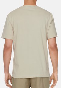 Beige T-Shirt mit kurzen Ärmeln und klassischem Rundhalsausschnitt. Weicher Baumwollstoff, schlichtes Design, mit geradem Saum und ohne sichtbare Logos.