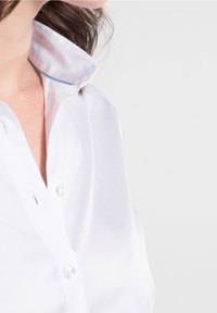 Chemise blanche à poignets boutonnés avec une texture douce et lisse, dotée d'un col avec un accent bleu et une rangée de boutons sur le devant.