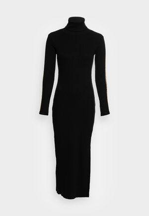Robe noire à manches longues et col montant, avec une coupe ajustée et une texture côtelée, présentant une fente sur le côté et des accents dorés le long des manches.