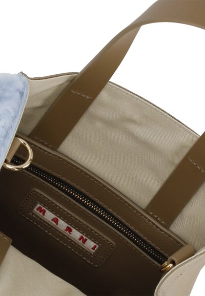 Borsa a tracolla beige con manici in pelle marrone, interno foderato e un accento di pelliccia azzurro chiaro. Include una tasca con zip con un'etichetta del marchio.