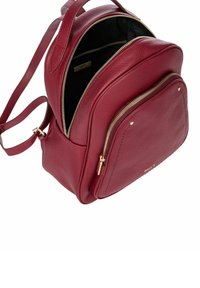 Sac à dos en cuir rouge avec une forme arrondie, une poche zippée extérieure, des éléments en métal doré et une finition texturée. L'intérieur présente une doublure noire.