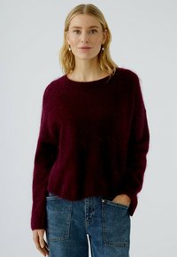 Bordeaux wollen mix trui met een ontspannen pasvorm, ronde halslijn en geribbelde mouwen, gecombineerd met high-waisted denim jeans.