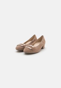 Ballerines en suede beige avec un bout rond, un petit talon carré et une bande décorative à l'avant. Doublure intérieure lisse.