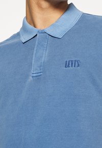 Polo bleu clair en tissu texturé, doté d'un col et d'un logo Levi's subtil brodé sur la poitrine.