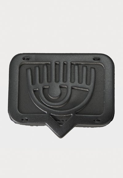Black rubber object featuring an embossed eye and hand design, rectangular shape with rounded corners, and a triangular base for attachment.