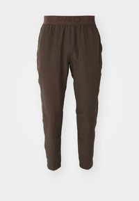 Pantalons de sport marron avec une taille élastique. Fabriqués dans un matériau léger, avec un design à jambe fuselée et des poches latérales. Sans motifs.
