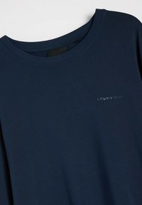 Granatowa koszulka z okrągłym dekoltem, wykonana z miękkiego materiału. Z przodu znajduje się subtelne logo "diverse" w jaśniejszym odcieniu, wyszyte na tkaninie.