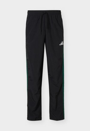 Pantaloni sportivi neri con vita elastica e coulisse, strisce laterali verdi e logo Adidas bianco sulla parte superiore della coscia sinistra.