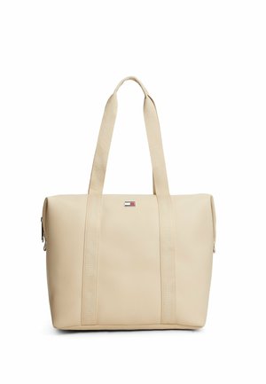 Beige rektangulær taske med lange håndtag og en lille rektangulær logopatch i midten foran.