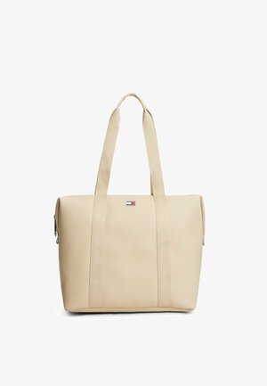 Beige rektangulær taske med lange håndtag og en lille rektangulær logopatch i midten foran.